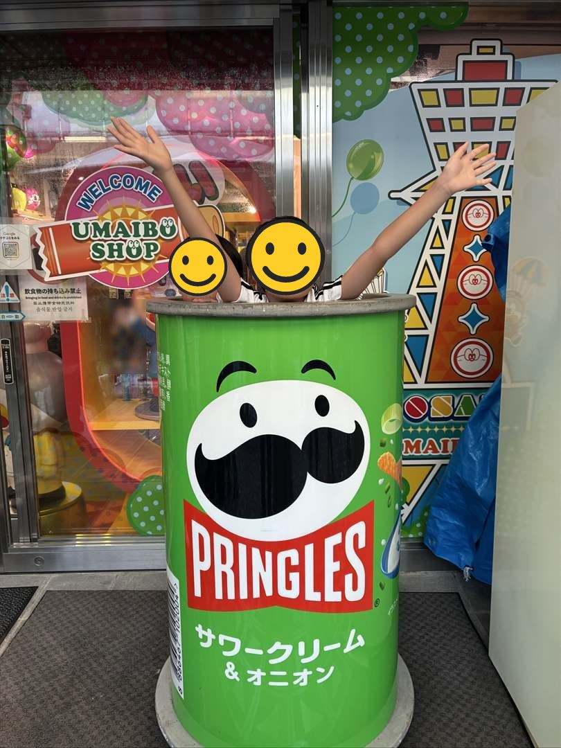 新世界のうまい棒ショップの前で、大きなプリングルズの缶から顔を出してバンザイする兄弟