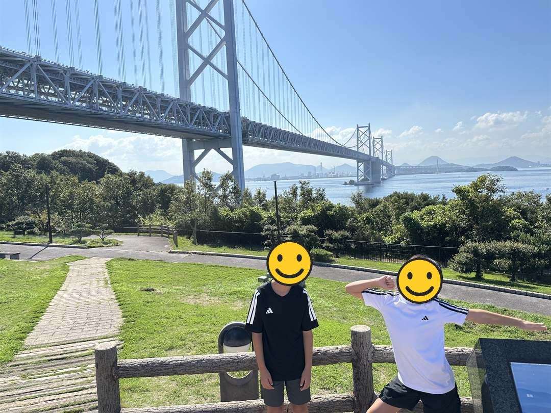 与島PAの展望広場から見上げた瀬戸大橋と、芝生でポーズをとる兄弟