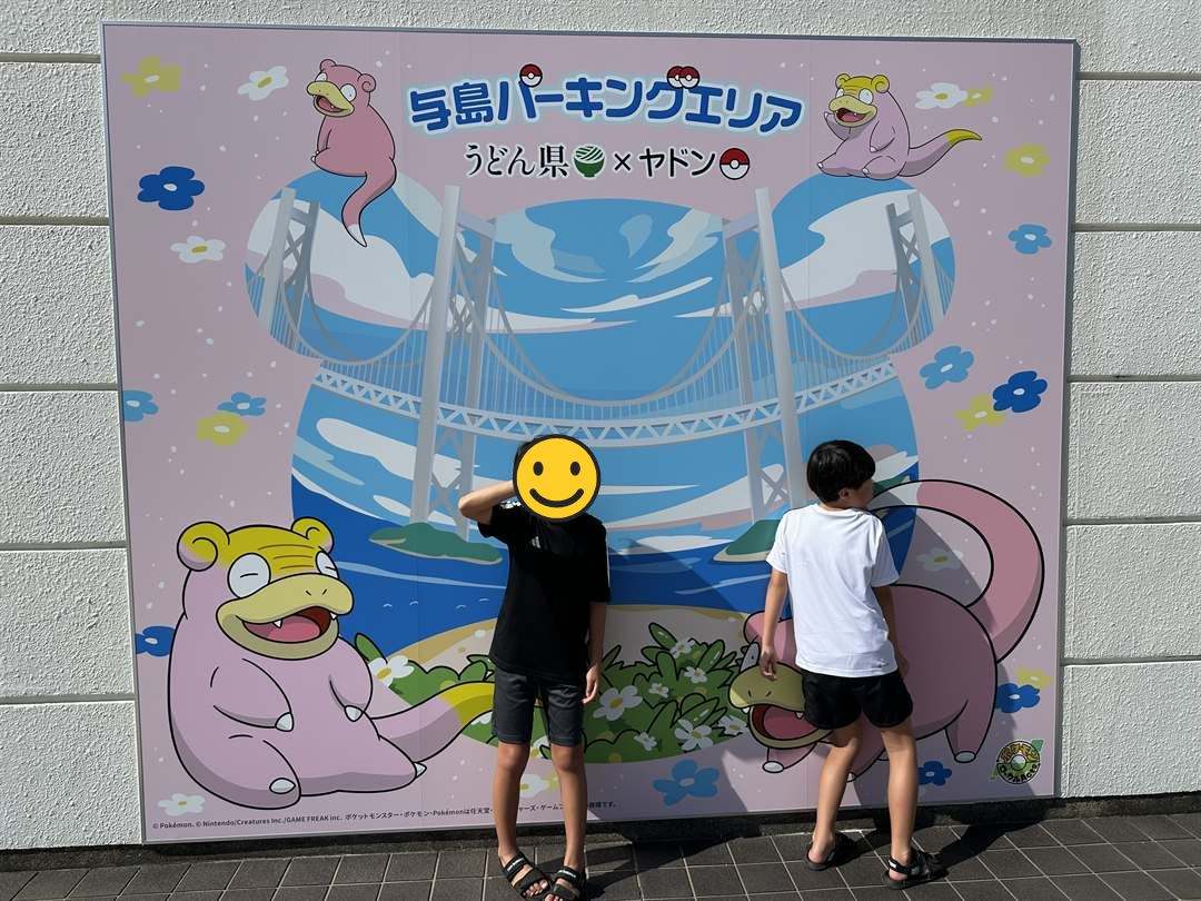 与島パーキングエリアの「うどん県×ヤドン」のパネルの前でポーズをとる兄弟