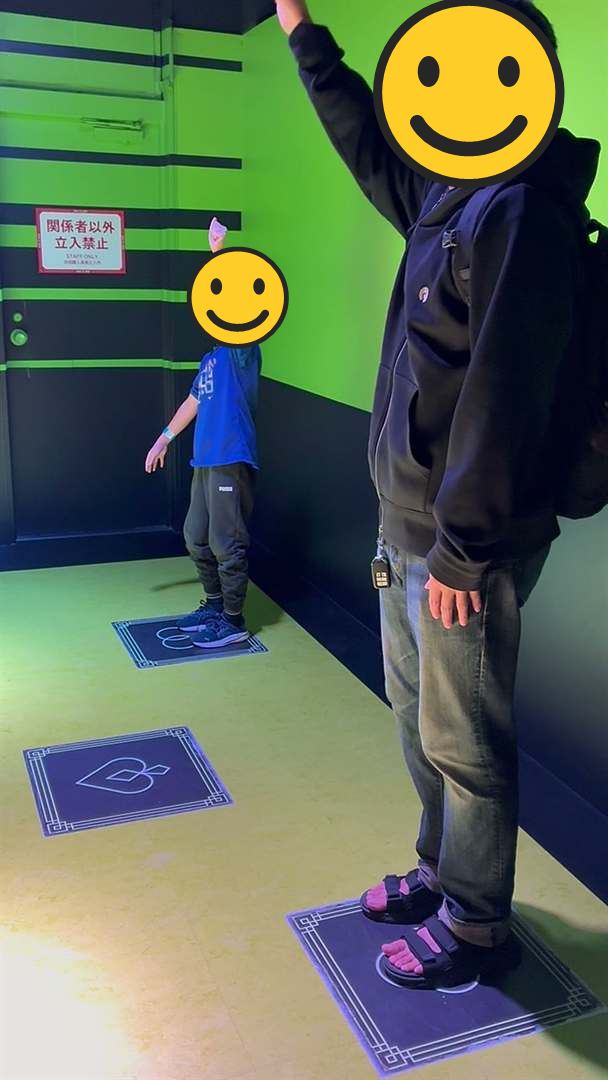 絶望要塞の旗あげのゲームで、足形のマスの上に立って手を上げるパパとこども