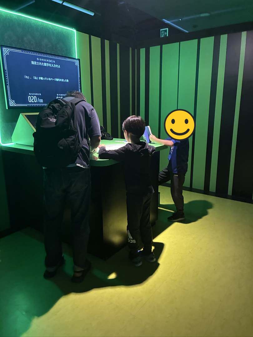 絶望要塞のイライラ本の部屋で、机の上の本をめくって答えを探すパパとこども
